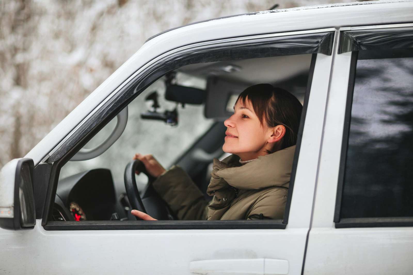 Happy woman driving car in winter